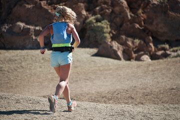 Female athlete run mountain race with hydratation trail vest for running