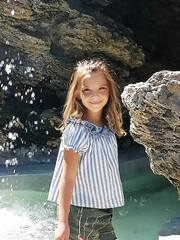 beautiful little girl staying at the rocks near the sea