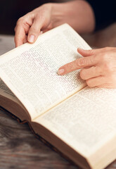 Fototapeta premium Hands, person and reading bible with religion, peace and gratitude with faith, spiritual and praise. Closeup, believer and follower with holy book, guidance and personal growth with worship and home