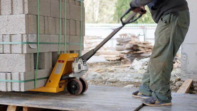 At a construction site, a worker transports concrete blocks on a dolly, facilitating construction activities