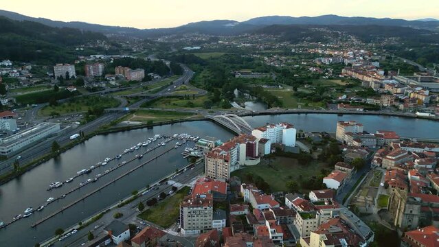 Aerial drone view of Marina of Pontevedra and part of the city.  View of Lerez River and Correntes Bridge. Travel destination in Galicia. Urbanisations on hills. Sunset point. Drone forward