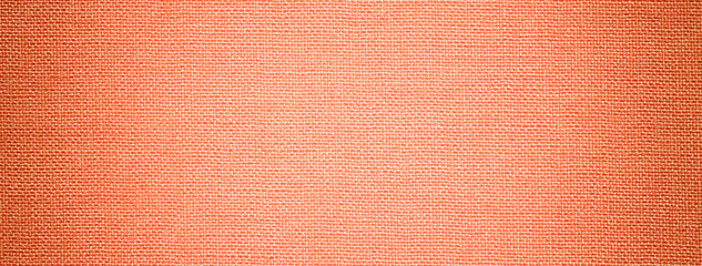Fototapeta premium Dark coral background from textile material with wicker pattern, and vignette. Peach fuzz fabric with texture.