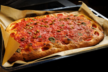 Cooking a homemade focaccia with classic tomato sauce.