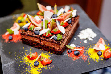 The chocolate cake adorned with fresh fruits and mint leaves.