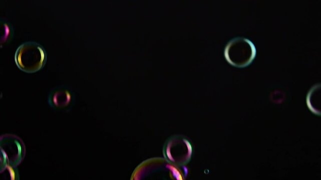 Soap bubble background. Colorful soap bubbles fly across black background. slow motion