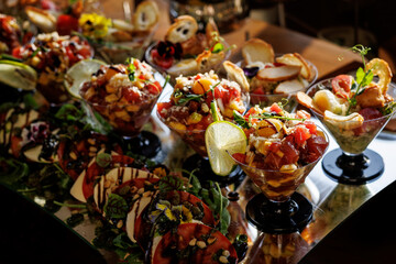 Glass cups hold layered salads, garnished with zesty lime slices, while surrounding plates feature additional salads and accompaniments