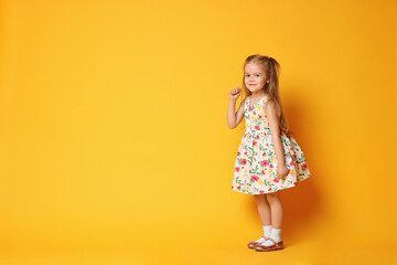 Cute little girl dancing on orange background, space for text