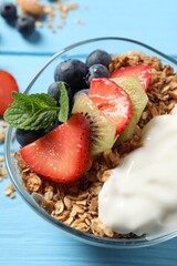 Tasty granola with berries, yogurt and mint on light blue wooden table, closeup