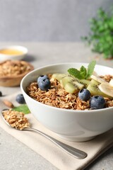 Tasty granola with fresh fruits on grey table, closeup