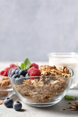 Tasty granola with berries, nuts and mint on grey table