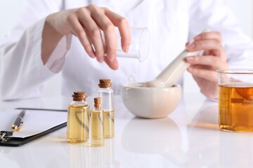 Aromatherapy product. Scientist developing essential oils at white table in laboratory, focus on...