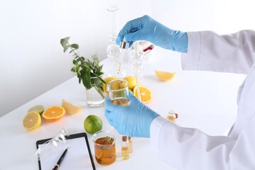 Aromatherapy product. Scientist developing essential oils at white table in laboratory, closeup