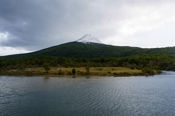 Snow-capped Andean mountain and beautiful green forest on the banks of a river, in Tierra del Fuego National Park, Ushuaia - Argentina, Tierra del fuego