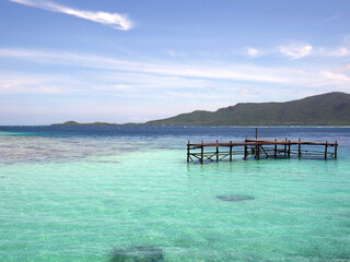 tropical beach with turquoise waters with wooden pier