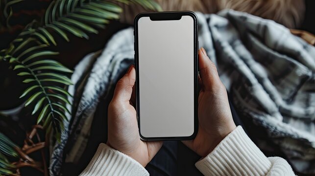 Close-up of adult hands gripping a smartphone, blank screen visible