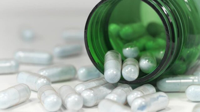 Overdose or poisoning. High doses and side effects. Blue capsules and jar lies on table. Pharmaceutical substance, drug treatment, harm from medications. Pharmacological biochemistry, drug therapy