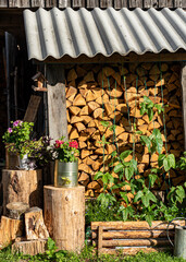 firewood pile decorated with flowers and garden objects, firewood stock for winter, garden decorations, summer