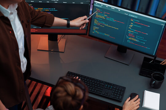 Top view of IT developers discussing with point to intelligent website development coder system running data online two screens information technology at neon light room at modern office. Infobahn.