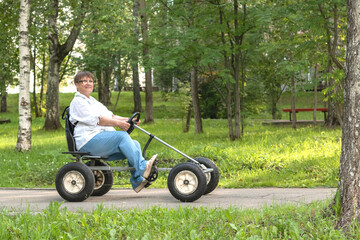 An elderly woman rides a toy car.