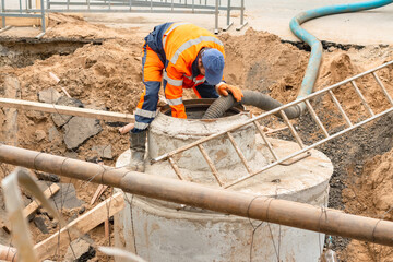A worker is pumping water out of a manhole.