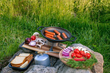 Cooking food in a frying pan, near a fire in the open air.