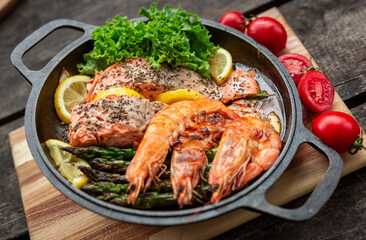 Healthy baked salmon steaks with greens and asparagus in a black cast iron skillet. A delicious low-carb breakfast.