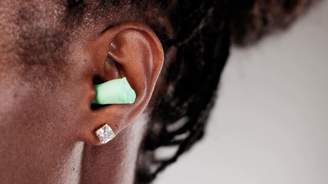 African American woman wearing a green earplug for noise protection at work