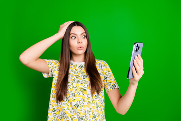 Naklejka premium Photo portrait of lovely teen lady hold device nervous amazed dressed stylish flowers print garment isolated on green color background