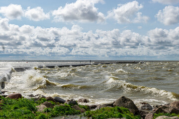 seascape, sea during a storm, splashing waves on the jetty, fast moving clouds