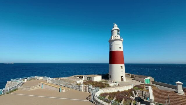 Europa Point Lighthouse facing the strait of Gibraltar on top of sea cliffs with the mountains of Morocco in the distance