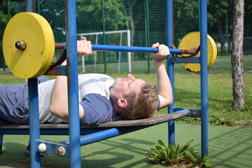 A dedicated young athlete puts in the hard work, vigorously training on gym equipment outdoors to...