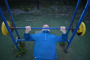 A dedicated young athlete puts in the hard work, vigorously training on gym equipment outdoors to...