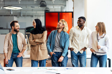 Diverse team of professionals smiling and chatting during break time in modern office
