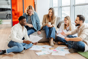 Fototapeta premium Marketing team having brainstorming session discussing documents on the floor