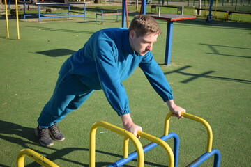 A dedicated young athlete puts in the hard work, vigorously training on gym equipment outdoors to...