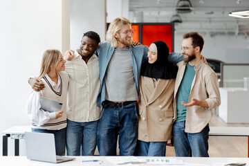 Group of five diverse business people smiling and posing for a photo in their modern office