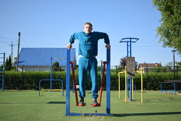 A dedicated young athlete puts in the hard work, vigorously training on gym equipment outdoors to prepare his body. He builds strength and endurance before hitting the field or court for competition