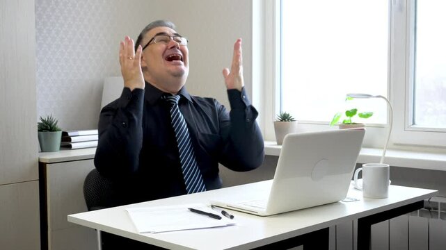 A businessman in the office ecstatically shouts while looking at the computer screen. Ideal for content on making right decisions, successful investments, and lucrative contracts.
