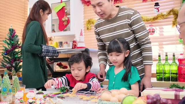 Happy Asian family spending times to prepare Chritsmas and Happy news year Celebrete. kids parent and grandparent doing ginger breads and bakery enjoy and dancing in kichen at home