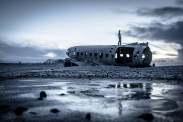 A man stands on the side of a crashed airplane