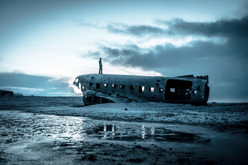 A man on the crashed military plane in Solheimasandur in winter with icy ground