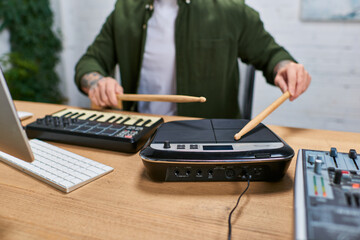 A handsome Asian man plays a drum pad in a studio setting. © LIGHTFIELD STUDIOS