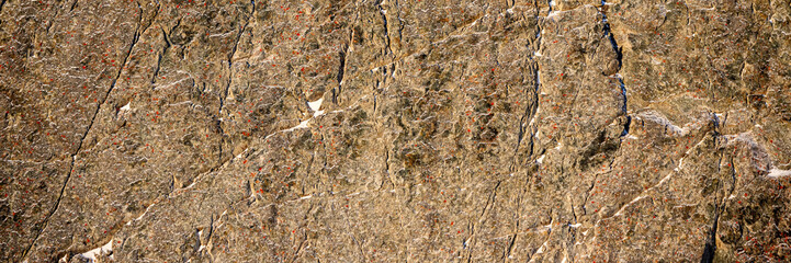 Rock texture. Snow and cracks on the surface of the cliff. Natural stone background.