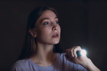 Woman scared holding hand flashlight in darkness and afraid of violence criminal robbery