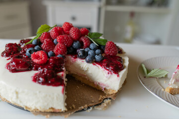 No bake cheesecake with fresh berries and berry compote on kitchen counter. Homemade summer cake