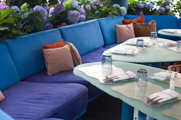a soft sofa in blue tones and chairs in a cafe, restaurant. A recreation area, a summer veranda and serving tables