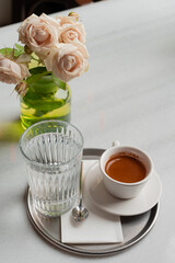 coffee and flowers. close-up of single serving espresso with fresh cut flowers