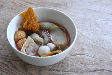 boiled fish and shrimp ball couple dumpling topping pickled cuttlefish in red soybean sauce soup on bowl