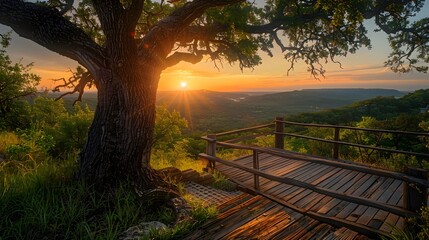 A wooden platform with railings, overlooking a valley and sunset in Texas at Indian Summer Mountain scenic spot. The sun sets behind trees atop the mountain, creating an enchanting atmosphere.