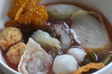 boiled fish and shrimp ball couple dumpling topping pickled cuttlefish in red soybean sauce soup on bowl